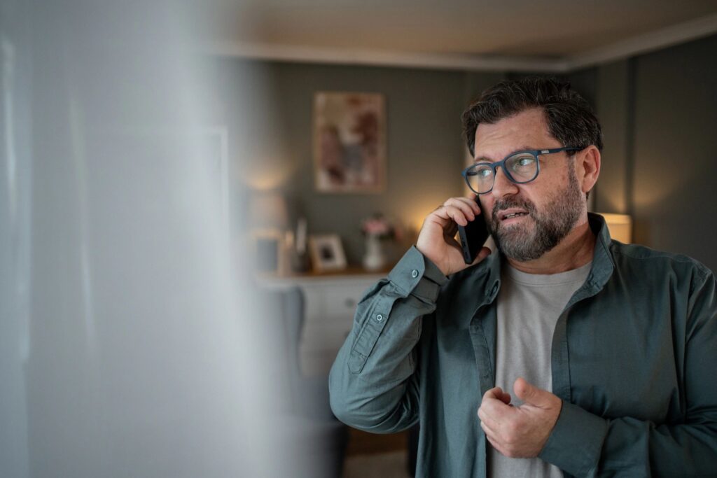 Worried mature man talking on smartphone at home